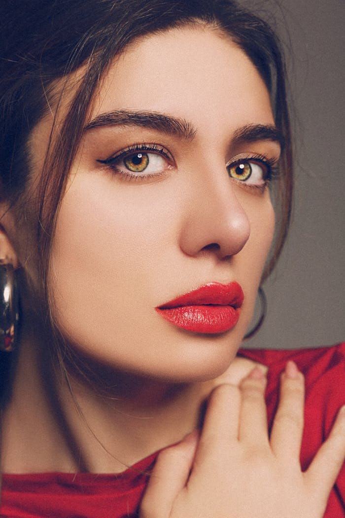 Elegant close-up portrait of woman with bold makeup and red lipstick.