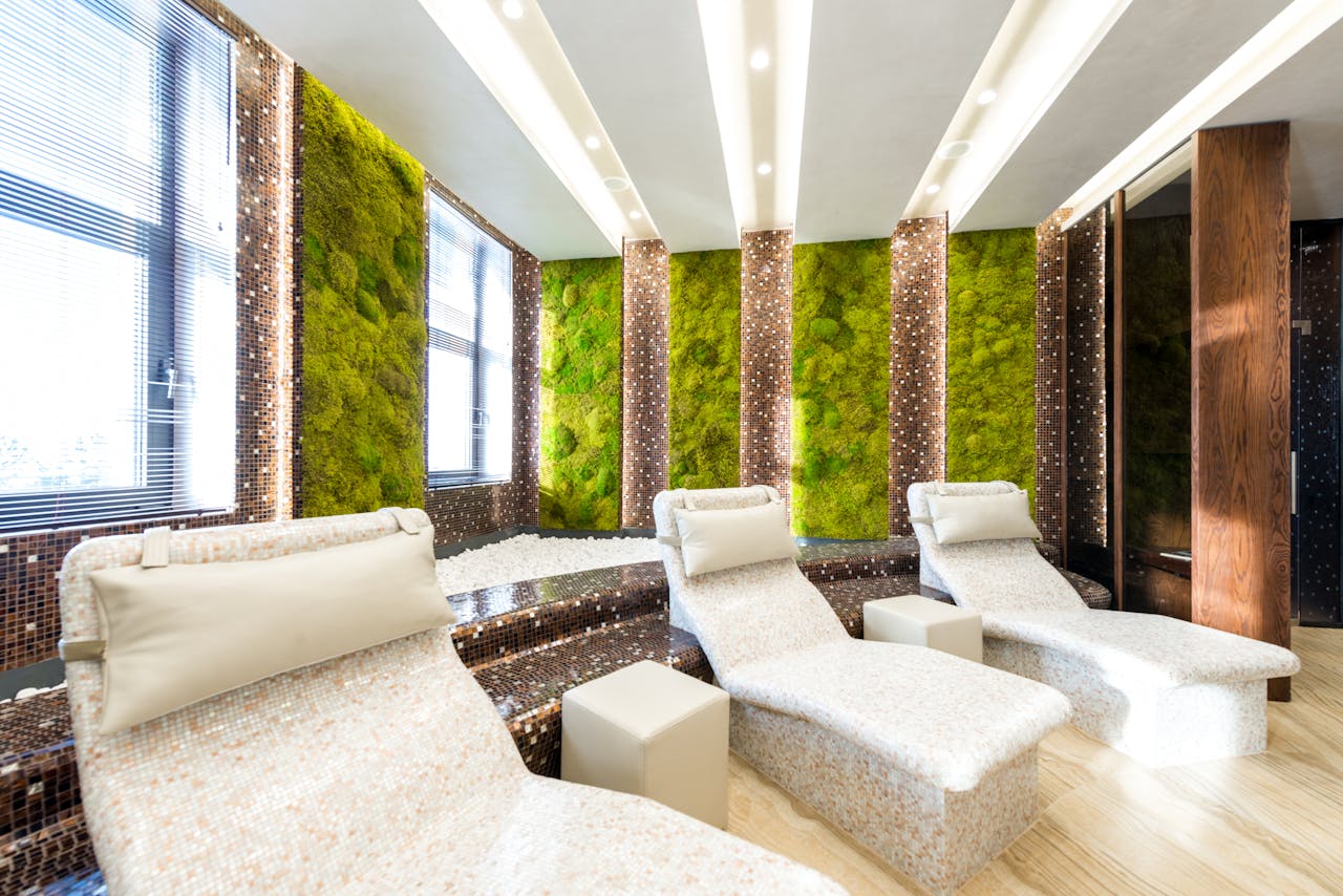 Modern spa lounge featuring comfortable loungers and vibrant moss walls for a relaxing ambiance.